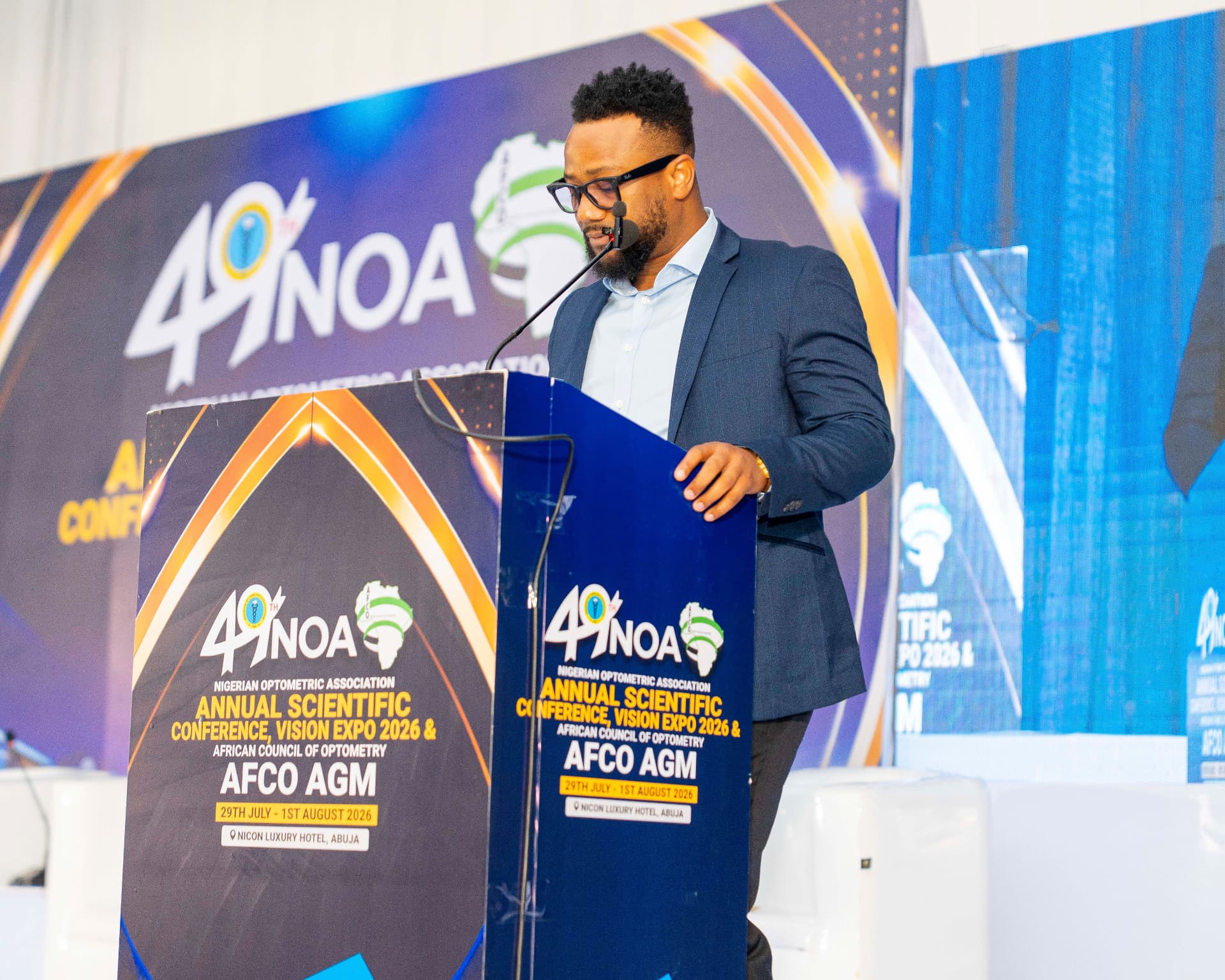 Dr JohnPaul Odigbo speaking at the AFCO/NOA podium with conference branding